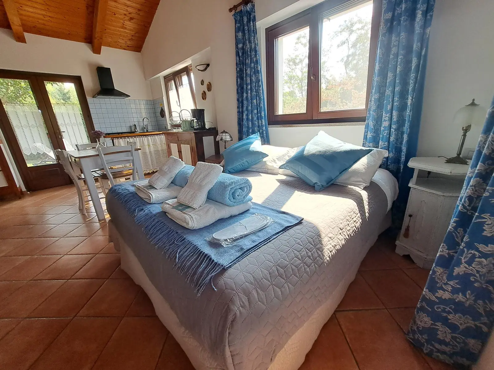 Ambiente unico del Ciabot di Rosa con letto matrimoniale, cucina e porta sul giardino