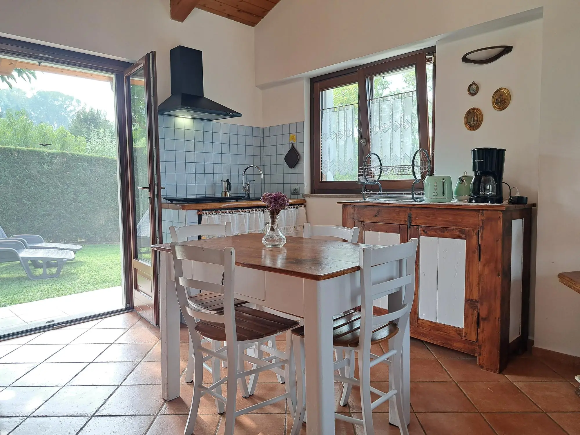 Equipped kitchen with wooden table and French window onto the garden