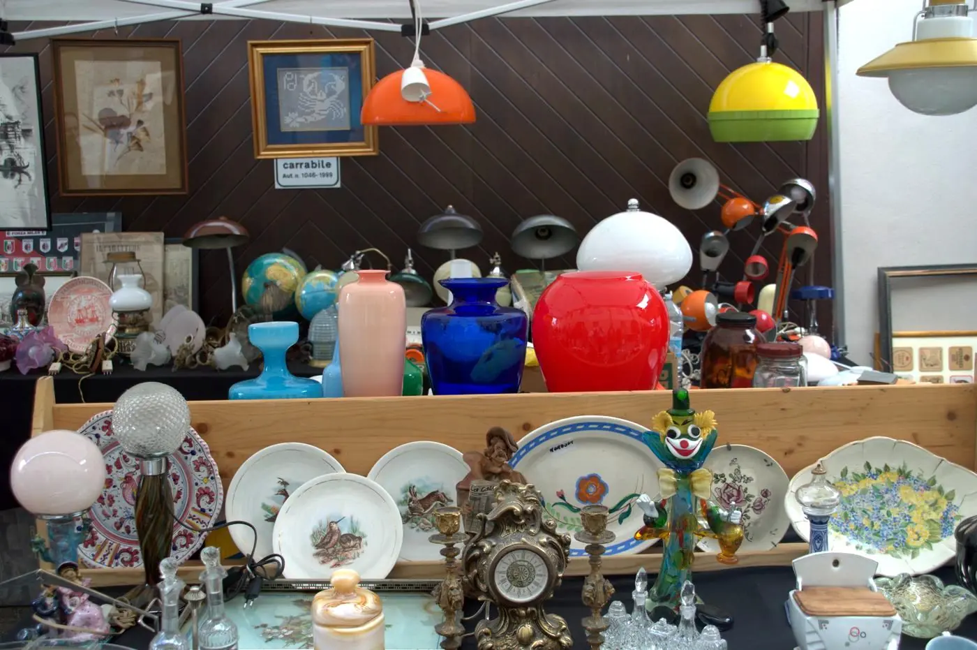 Banco del mercatino dell’antiquariato di Cherasco con vasi, lampade e piatti d’epoca